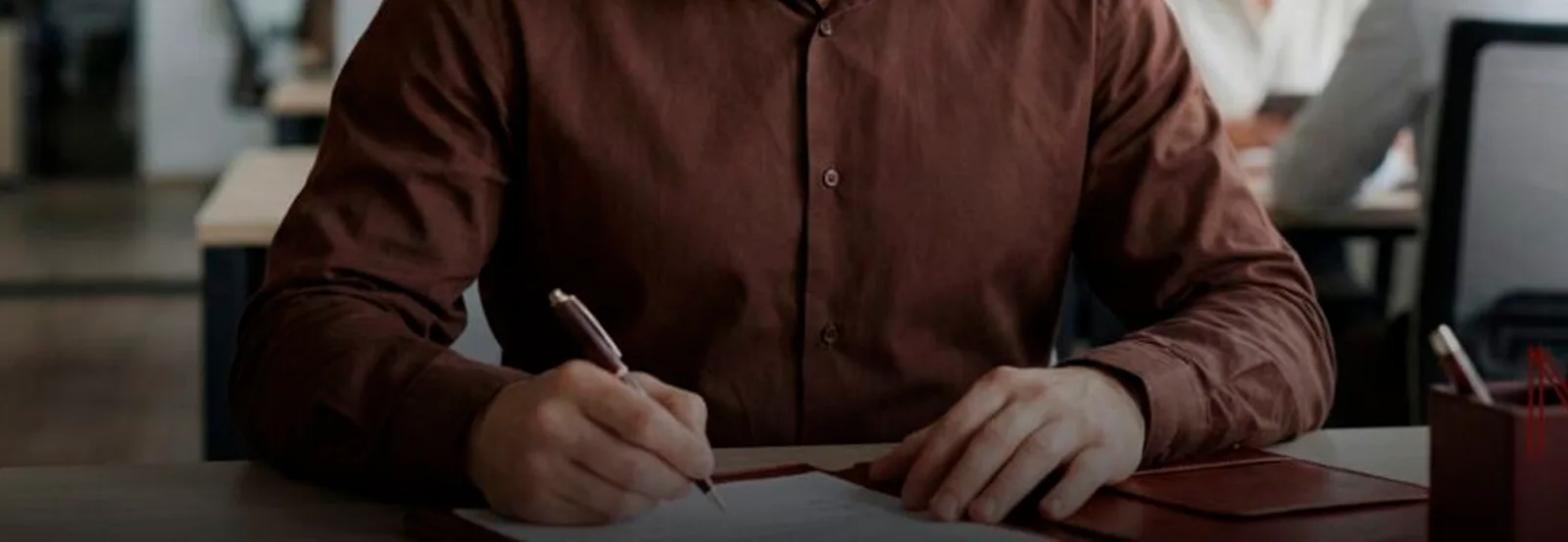 Pessoa assinando um documento em uma mesa de escritório